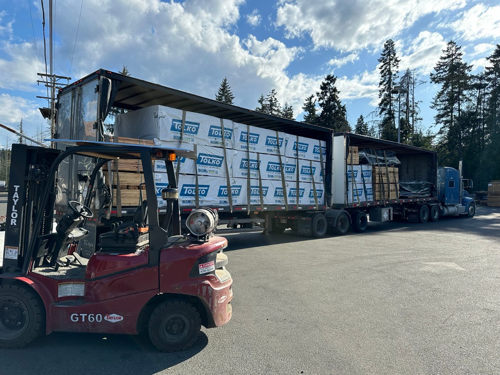 B-train of Tolko-wrapped lumber packs being unloaded by forklift in the Parksville yard